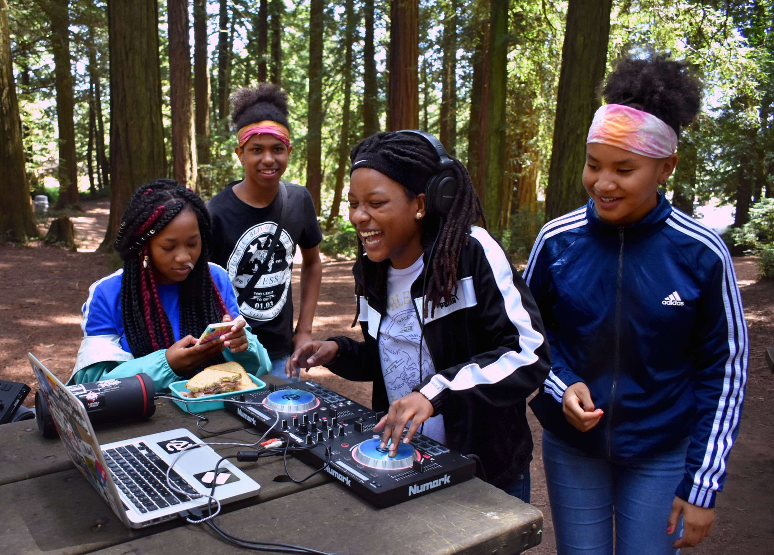 kids spin a turn table and laugh in a redwood forest